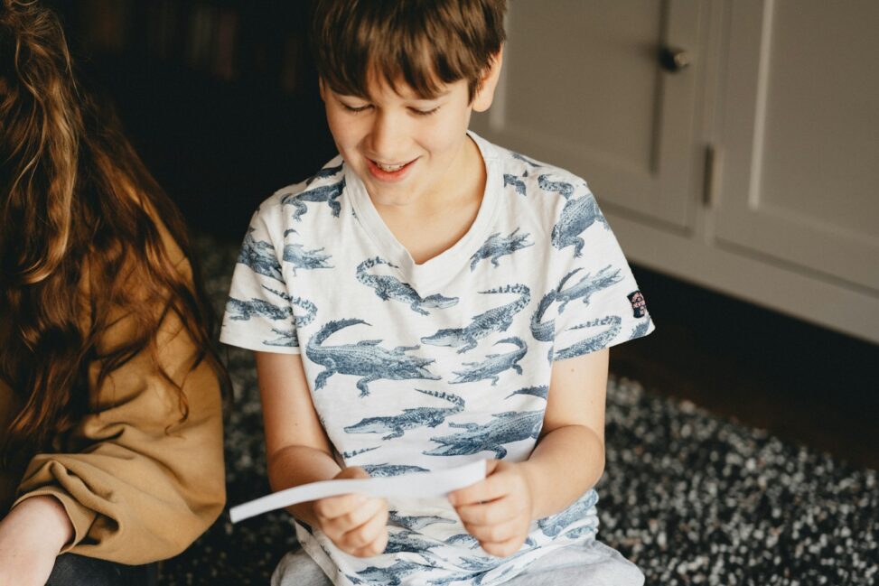 boy in white and blue floral button up t-shirt sitting on black and white textile